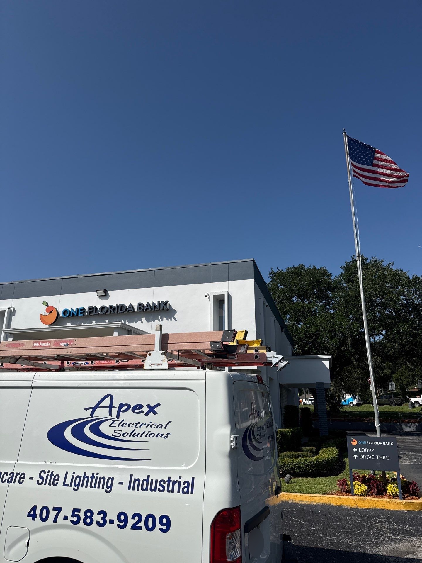 Apex Electrical Solutions vehicle parked in front of One Florida Bank and next to the United States of America flag